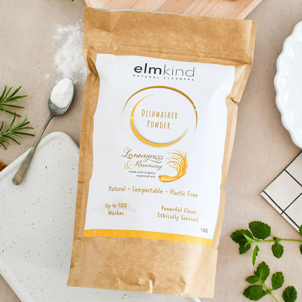 elmkind dishwasher powder 1KG, with lemongrass and rosemary essential oils in a brown plastic free paper bag on a kitchen surface with some fresh plants