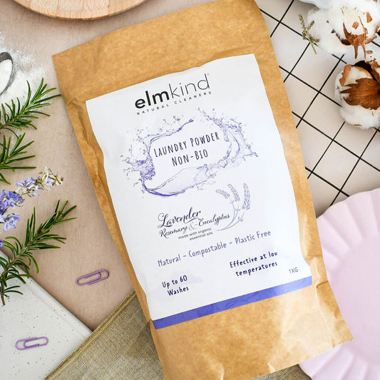 elmkind laundry powder 1KG lavender, rosemary and eucalyptus in a brown plastic free paper bag on a kitchen surface with sprigs of rosemary
