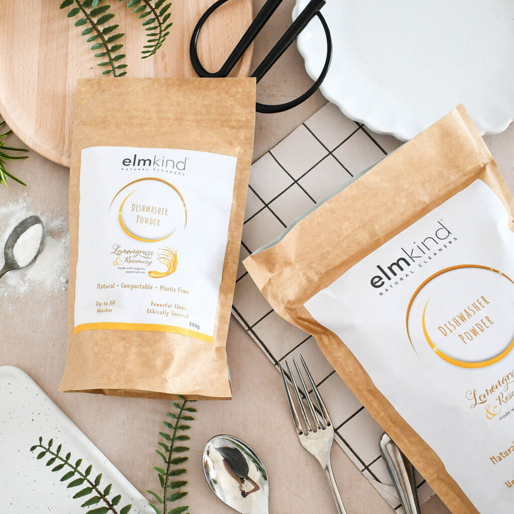 two bags of elmkind dishwasher powder 500g and 1KG, with lemongrass and rosemary essential oils in brown plastic free paper bags on a kitchen surface