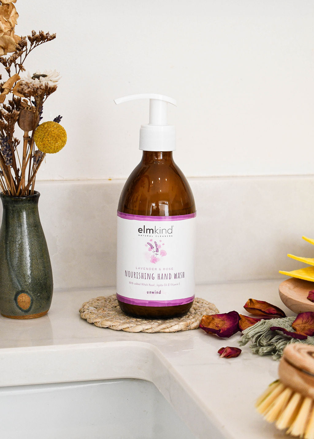 elmkind Lavender and Rose hand wash in a 250ml amber glass bottle with white plastic pump on a kitchen surface with some dried flowers
