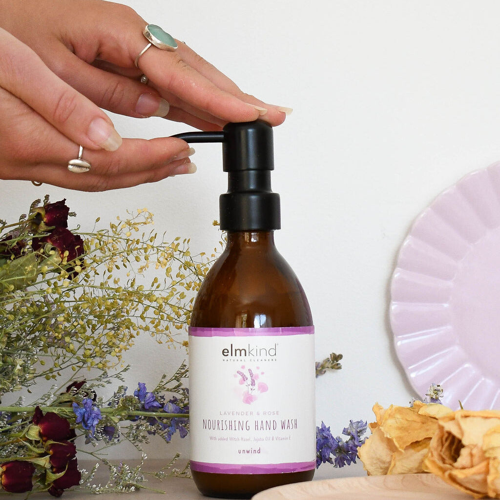elmkind Lavender and Rose hand wash in a 250ml amber glass bottle with black metal pump and a womans hands cupping the spout of the pump
